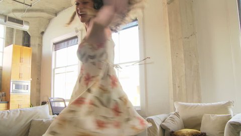 Woman in dress dancing while listening to headphones