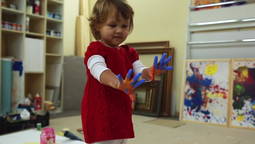 Adorable little girl pours a lot of paint on all studio.