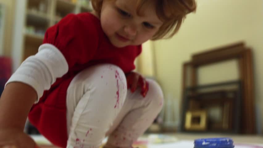 Adorable little girl pours a lot of paint on all studio.