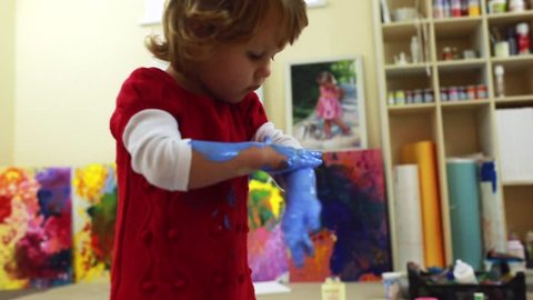 Adorable little girl pours a lot of paint on all studio.