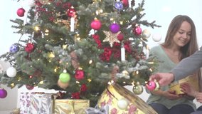 Christmas family. Parents presenting Christmas gift to their little daughter. Sitting on the floor near Christmas tree. Emotions and family values. Christmas celebration. HD video footage 1920x1080p