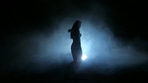 one sexy  woman stripper showgirl in silhouette studio isolated on dark background. Slow motion