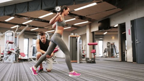 sport, fitness, lifestyle, weightlifting and people concept - woman and personal trainer doing lunge with barbell and flexing muscles in gym