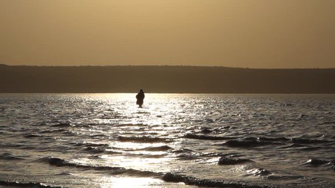 Man fishing in lake at sunset