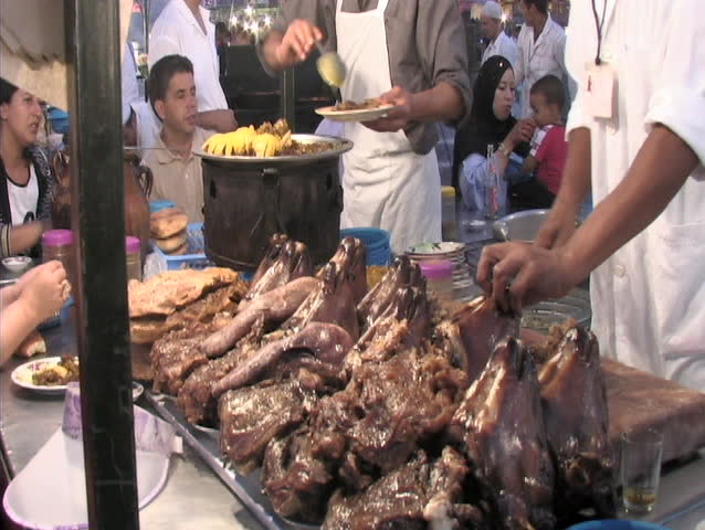 Moroccan man picking up a goat/lamb/sheep  head from buffet table