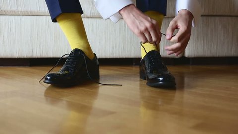 The man in a yellow socks wears shoes to tie shoelaces. 