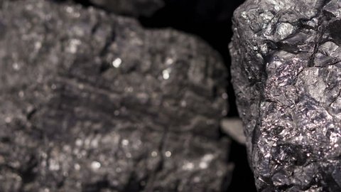 Shallow depth of field panning shot of a pile of carbon graphite raw ore at a mining installation.