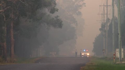 NINGI, AUSTRALIA - NOVEMBER 9 : Police holding cordon in front of bush fire front as it approaches houses November 9, 2013 in Ningi, Australia