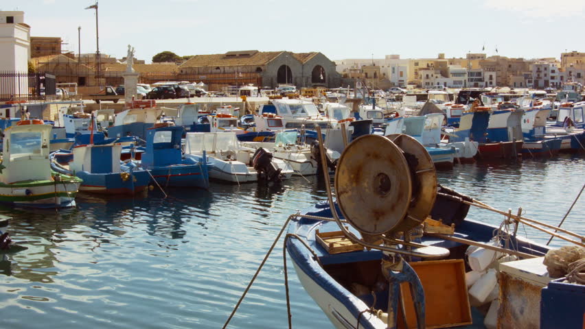 Mediterranean dock with small fishing ships and people walking in the distance
