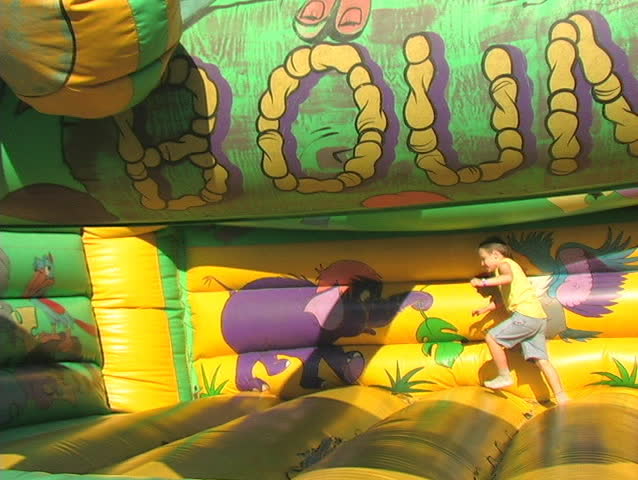 A SMALL BOY HAS FUN ON A BOUNCE RIDE AT AN AGRICULTURAL FAIR.
