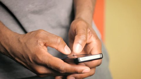 Hands of African American man sending text message on smart phone