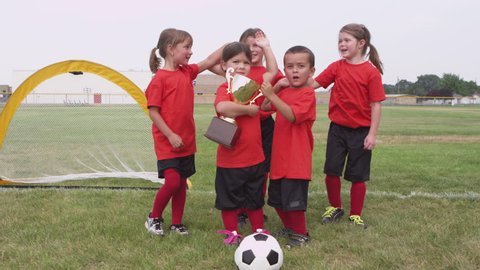 Children celebrating with trophy and soccer game Video Stok