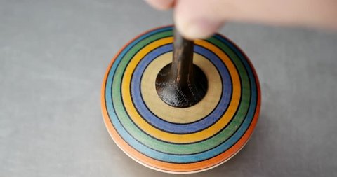 Close up shot of a spinning top moving on a silver surface/Spinning top