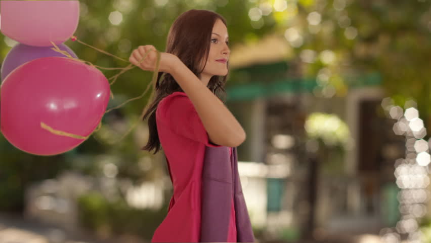 Dolly Shot Of Young Girl With Balloons In Park