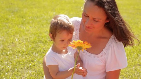 Mother And Baby Playing With Flower In Park