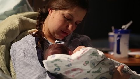A mother holding her newborn baby boy in a hospital bed directly after giving birth