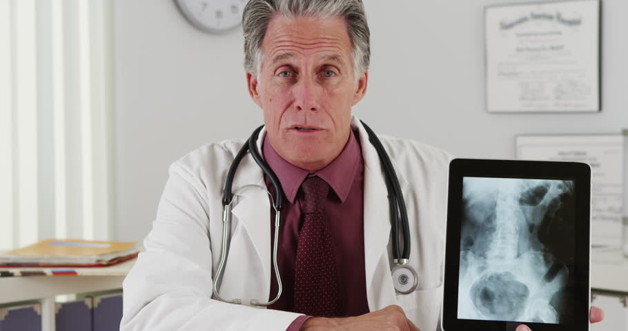 Senior doctor talking to camera with xray
