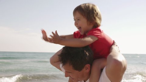 Happy Little Girl On Her Father's Shoulders At Beach.: stockvideo