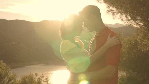 Dolly Shot Of Young Couple Hugging Overlooking Lake In Sunset.: film stockowy