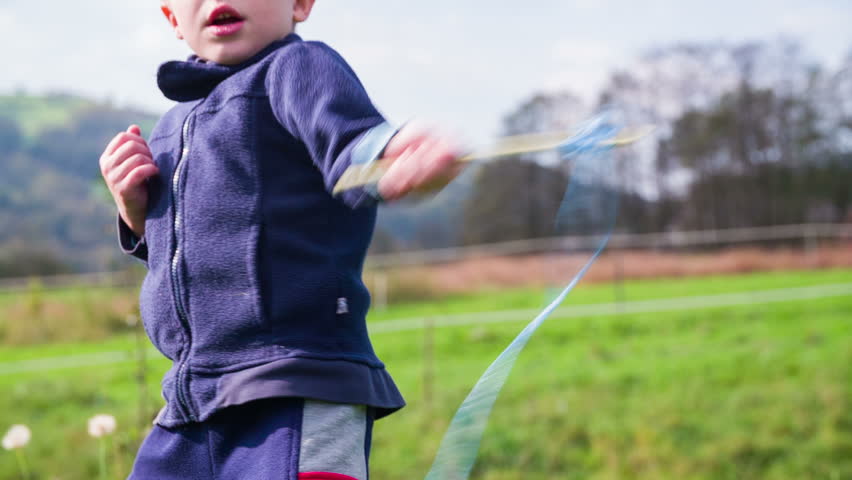 Playing with wooden sticks outside in slow motion. Boy spinning two sticks on a rope, playing ninja outside .