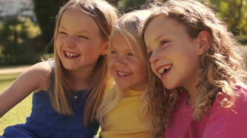 Three Girls Sitting On Grass Together In Park. : vidéo de stock