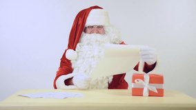 Happy Santa Claus reading a letter. Isolated on white background