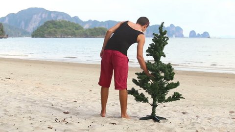 guy in beachwear makes a Christmas tree on the beach
