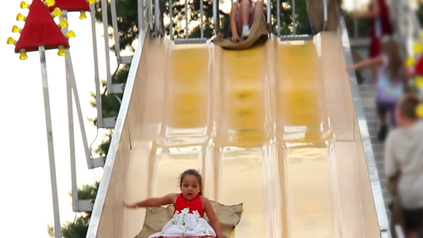 A girl slides down a large slide at a carnival.