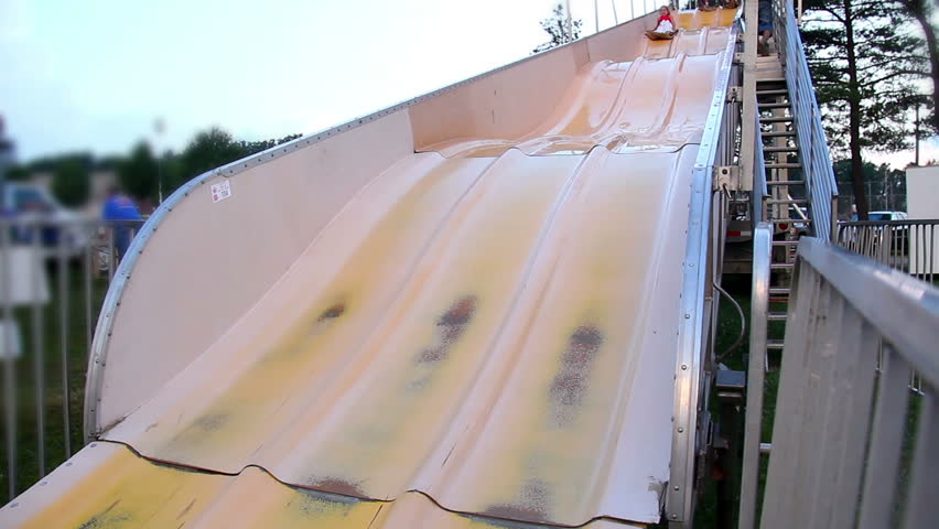 A girl slides down a large slide at a carnival.