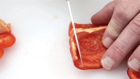 Very close video of a man slicing a red bell pepper for cooking.