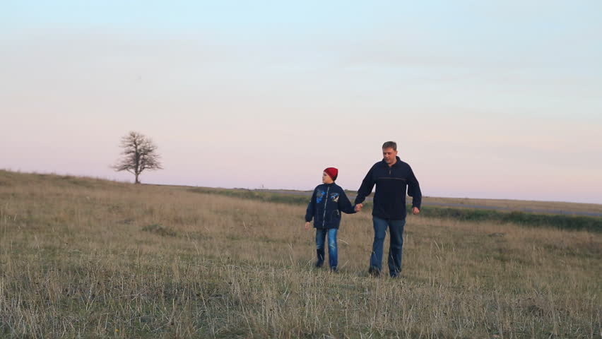 Happy caucasian father and son walking in a field. Teen child boy with father. Childhood dreams and memories. Happy family. 