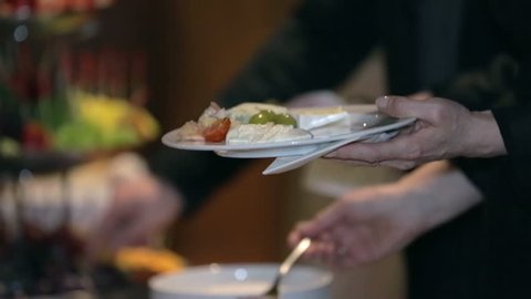 Man puts some food on his plate. Man puts some food on a white plate from catering in a celebration event in nice restaurant