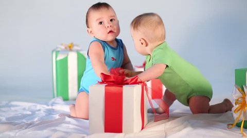 Two little babies playing with big gift box in the studio