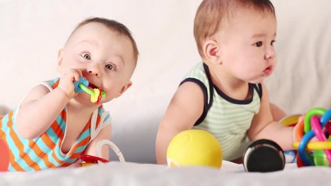 Two cute babies playing together with toys in the studio