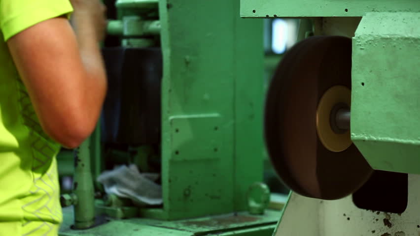 Footwear production - worker grinds boots 