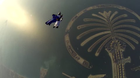 A group of skydivers in wingsuits gliding in the air over Dubai cityscape, POV