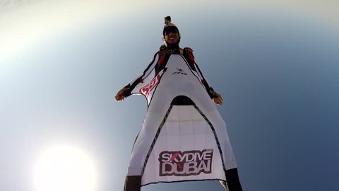 A group of skydivers in wingsuits swiftly gliding in the air over Dubai cityscape, POV