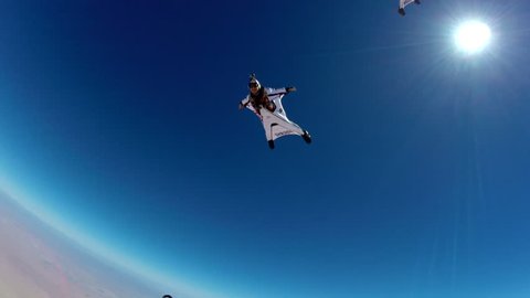 A group of skydivers in wingsuits swiftly gliding in the air, POV