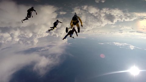 A group of skydivers passing through a layer of clouds while skydiving, POV