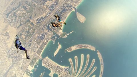 A group of skydivers jump together from a plane before skydiving over Dubai cityscape, POV