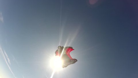 A skydiver in a wingsuit swiftly gliding in the air, POV