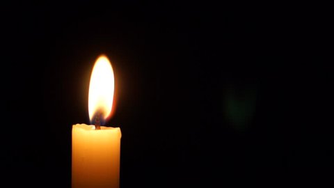 Single candle burning in the dark 