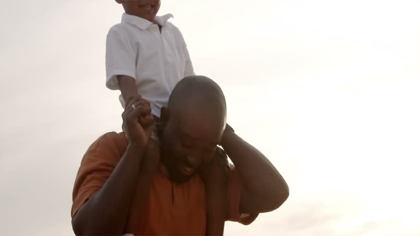 A father and son play in a wheat field on a sunny day.