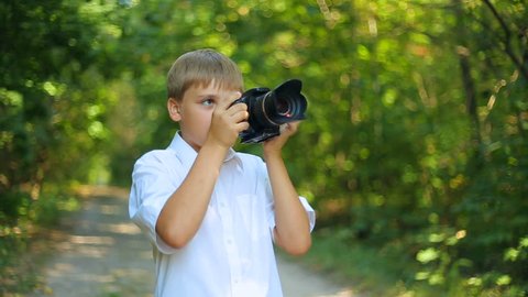 Happy caucasian child boy takes pictures and views photos on DSLR camera. Forest Nature and  animals protection, Ecology of Earth and environment, clean fresh air