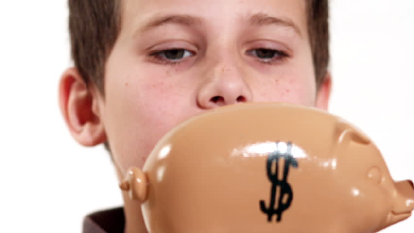 A young boy puts his money in a piggy bank and cannot get it out until he