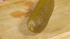 Pickled cucumber cutting piece with knife on wooden board 4K 2160p UHD footage - Gherkin piece on wooden table 4K 3840X2160 UHD viudeo