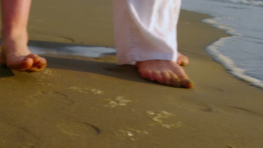 Older couple walk on the beach together. close-up of feet. 