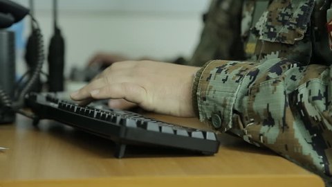 Soldier typing on computer keyboard in communication center