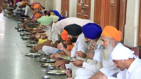 AMRITSAR, INDIA - SEPTEMBER 27, 2014: Unidentified poor indian people eating free food at a soup kitchen in the Golden Temple