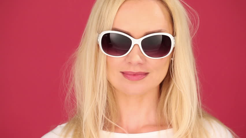 Vivacious young blond woman in trendy sunglasses smoking e-cigarette